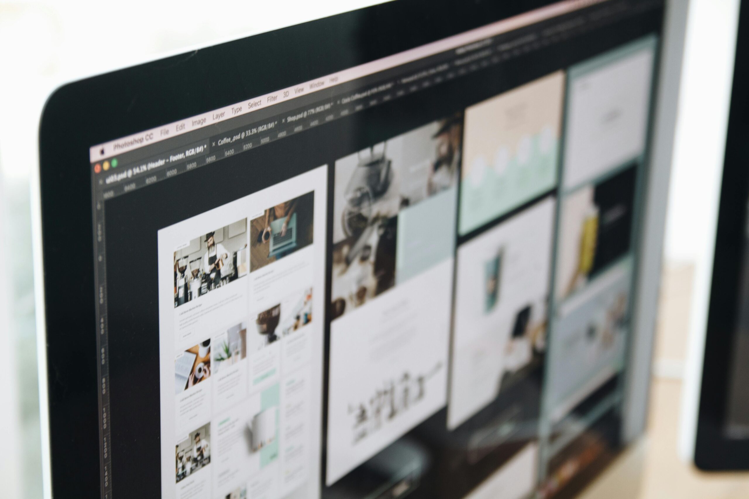 Desktop monitor showing website mockup layouts and web design interface in a creative design workspace.
